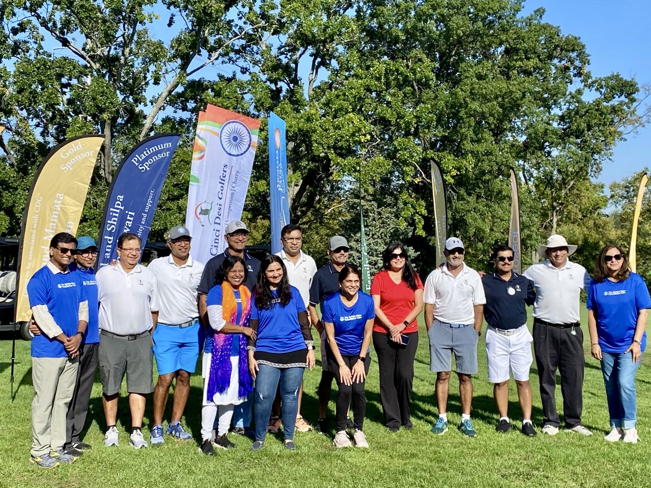 Large group photo with participants, volunteers, and sponsor banners including Indian flag